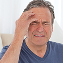 Middle aged man suffers from a headache at home