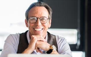 Pleasant mature businessman sitting at table with smile