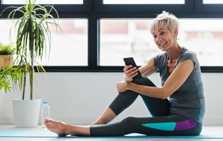 An active senior woman using smart phone at home after practicing yoga while monitoring her TMJ