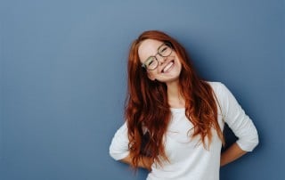 Cute red haired woman tilts her head and shows off her amazing smile